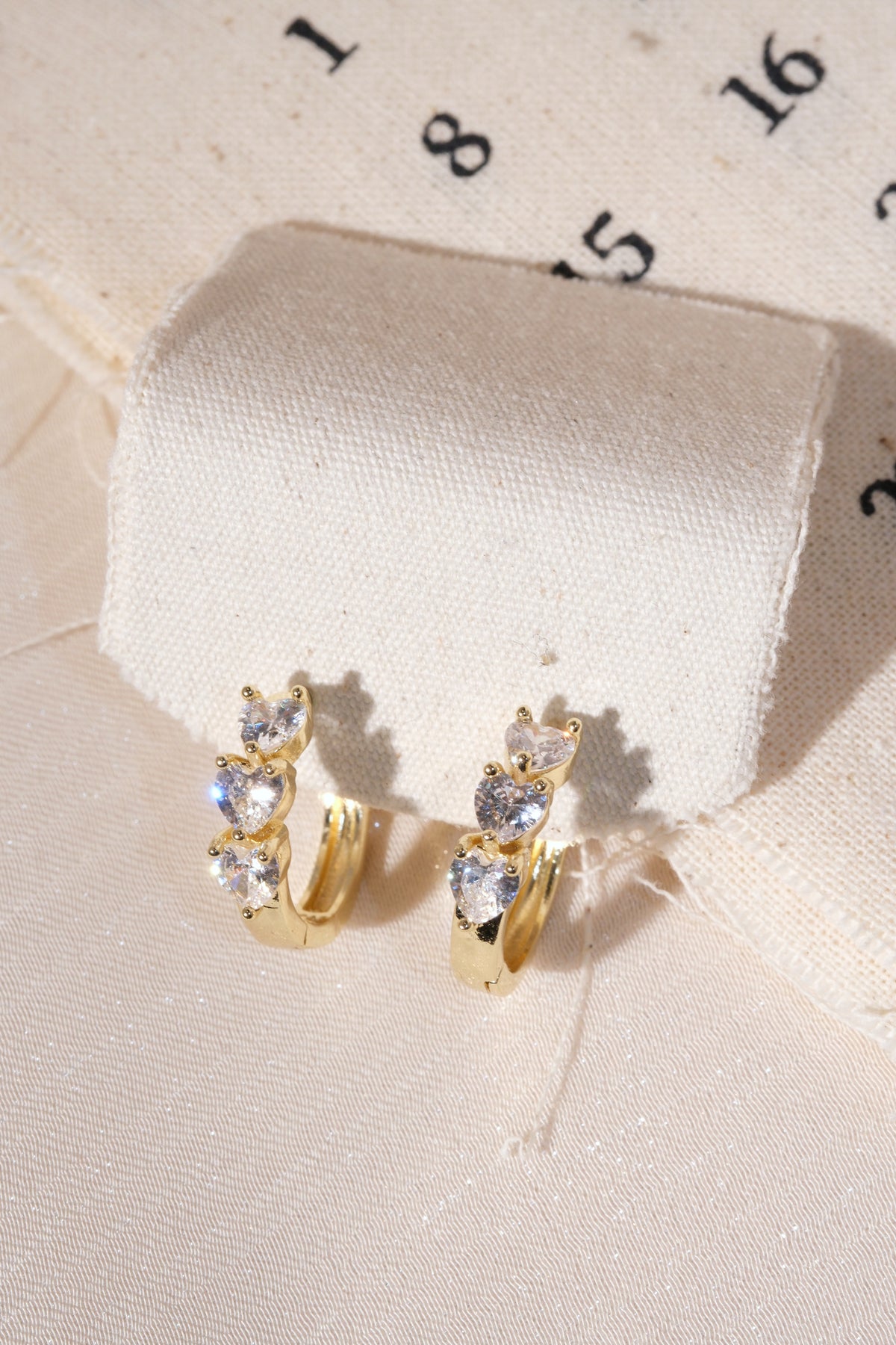 Gold Triple Heart CZ Huggie Earrings — edited real product photo