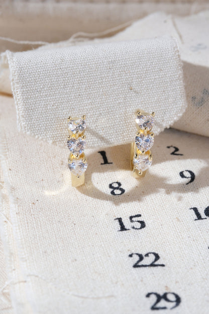Gold Triple Heart CZ Huggie Earrings — edited real product photo