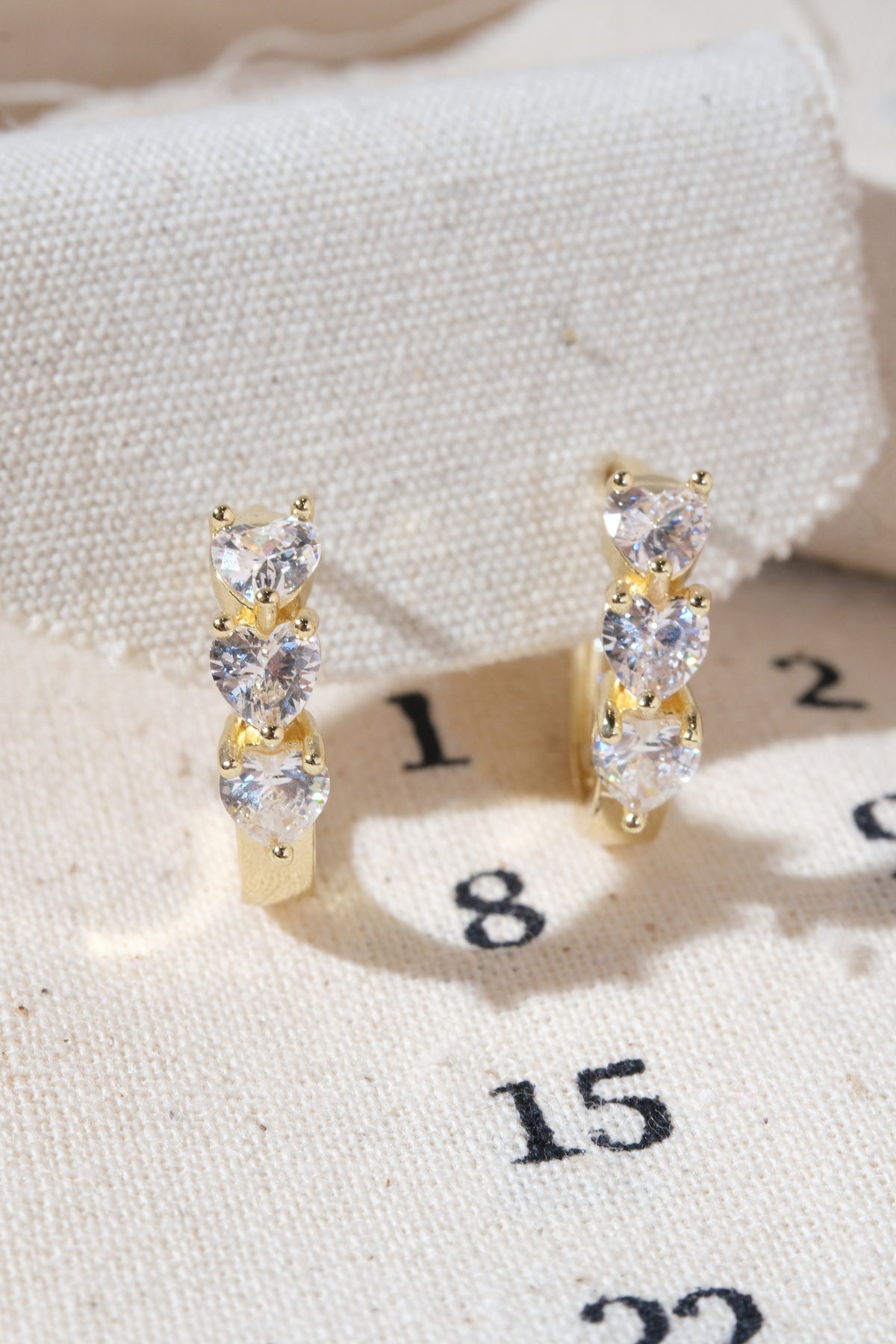 Gold Triple Heart CZ Huggie Earrings — edited real product photo