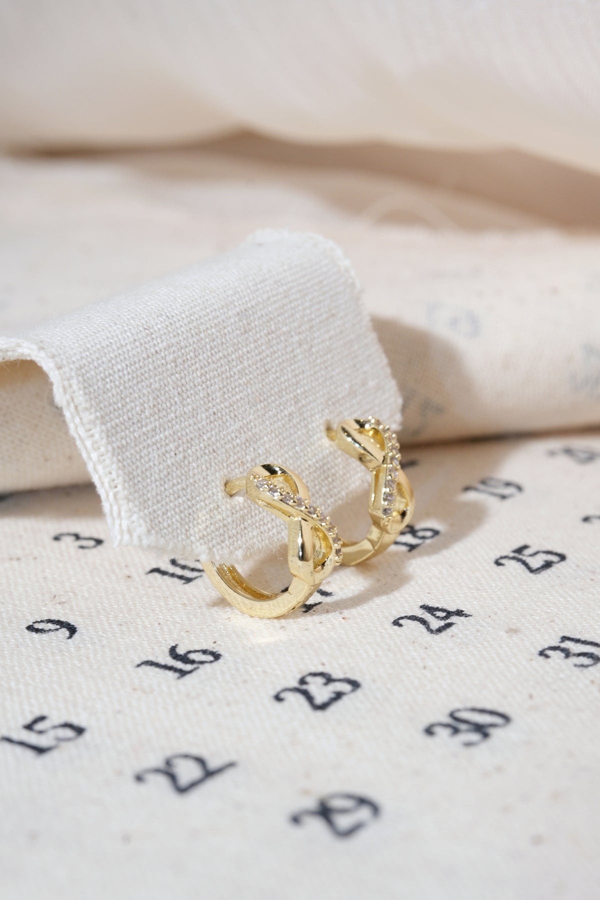 Gold Infinity CZ Huggie Earrings — edited real product photo